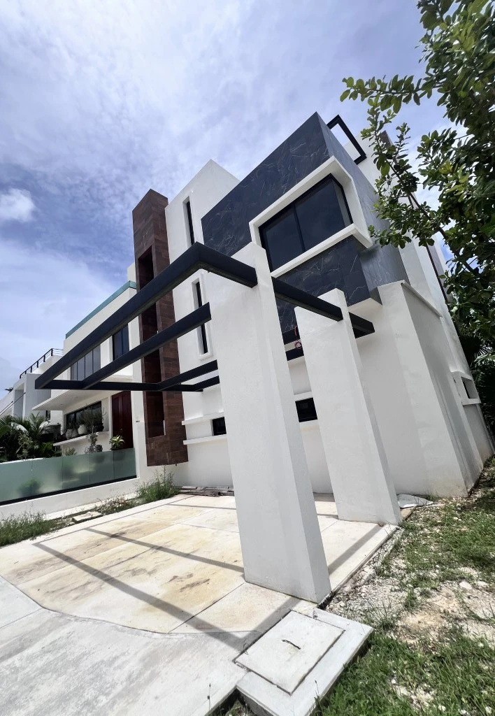 Casa blanca de tres niveles con pérgola negra en Cancún
